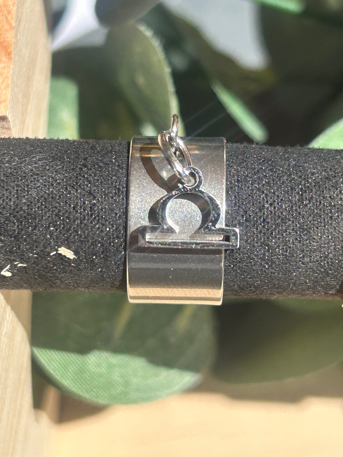 Bague Cassiopée à monture large en acier inoxydable argenté, avec une breloque du signe de la Balance suspendue.