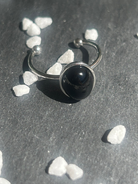 Bague Thémis réglable en acier inoxydable argenté, ornée d’un cabochon ovale en agate noire.