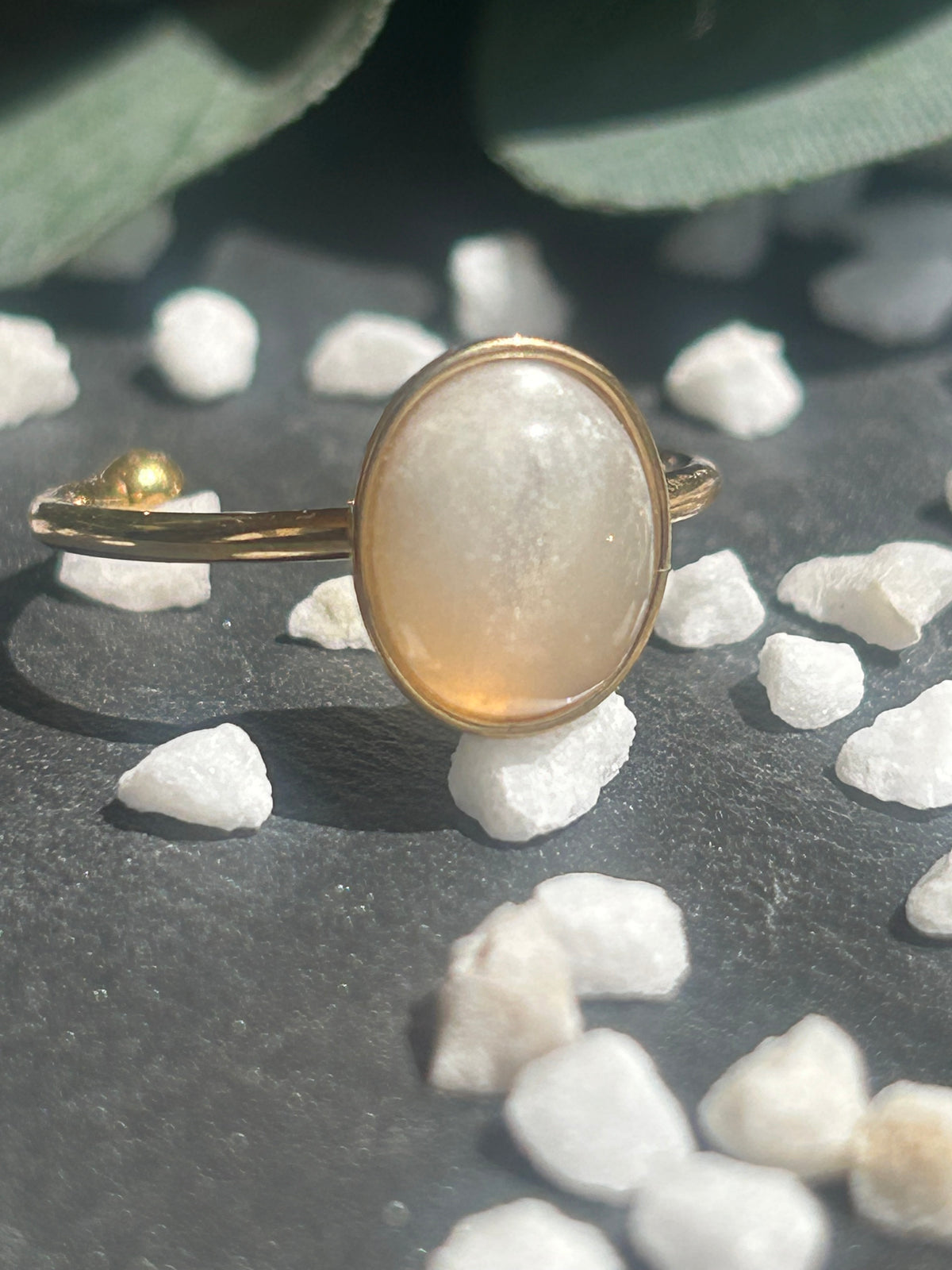 Bague Thémis réglable en acier inoxydable doré, ornée d’un cabochon ovale en pierre de lune blanche.