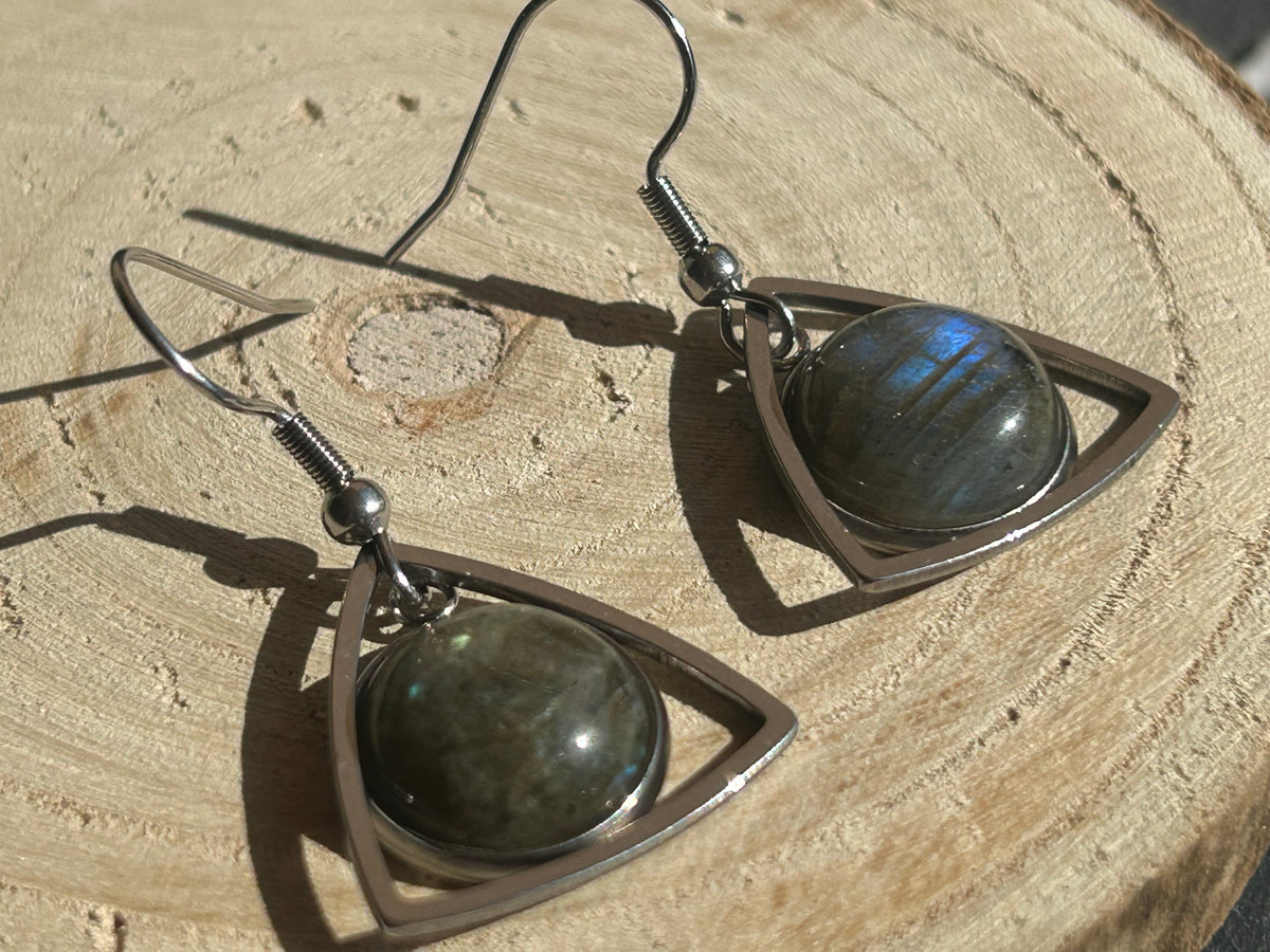 Paire de boucles d’oreilles pendantes Aeltria en acier inoxydable argenté, avec des montures triangulaires et des cabochons ronds en labradorite aux reflets bleus.