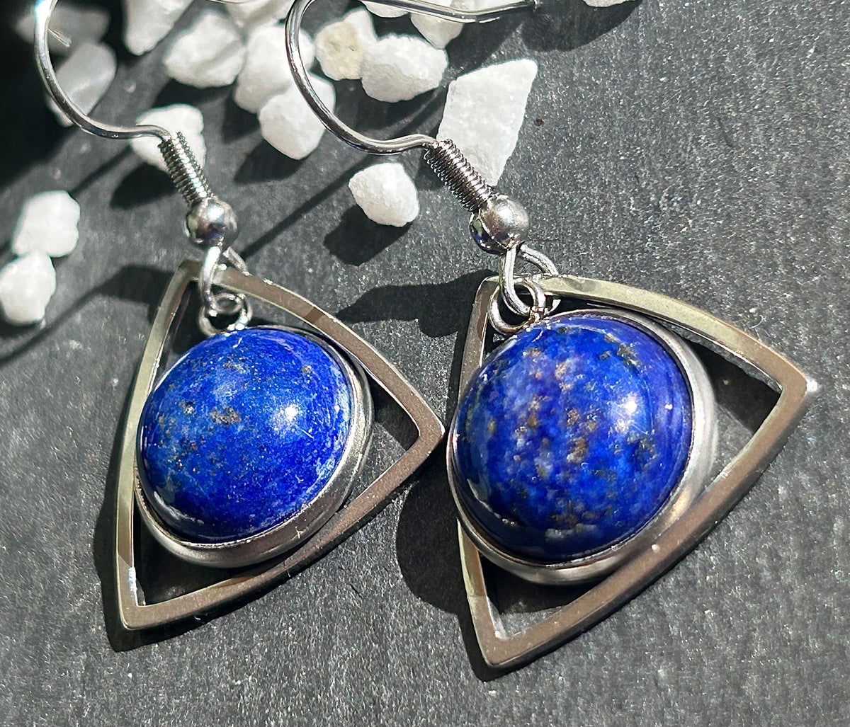 Paire de boucles d’oreilles pendantes Aeltria en acier inoxydable argenté, avec des montures triangulaires et des cabochons ronds en lapis-lazuli bleu profond.