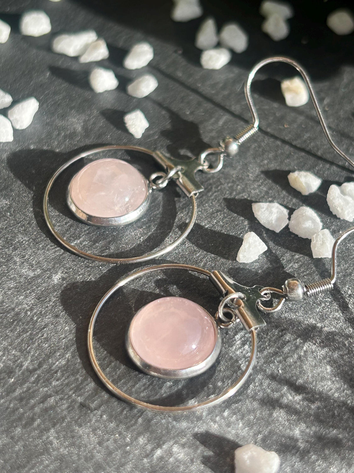 Paire de boucles d’oreilles pendantes Célestia en acier inoxydable argenté, avec des montures circulaires et des cabochons ronds en quartz rose pâle.