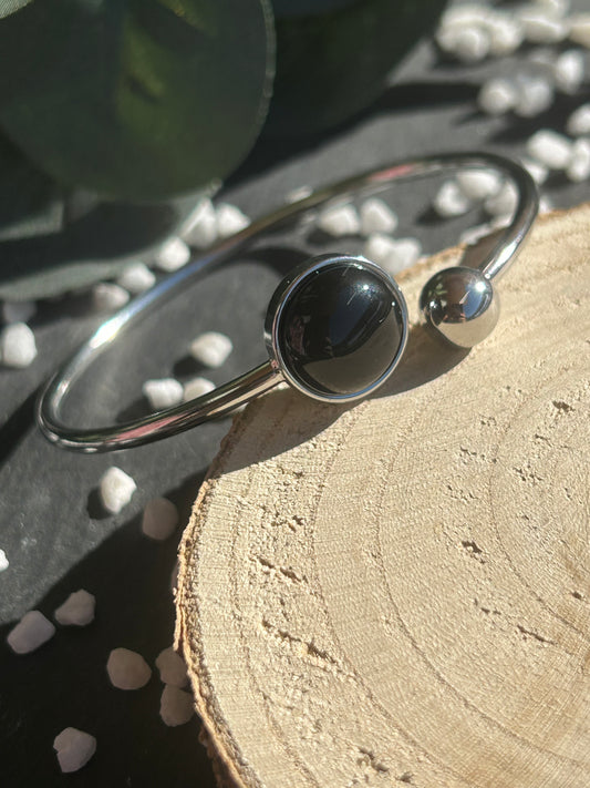 Bracelet jonc Lunae en acier inoxydable argenté, orné d’un cabochon rond de 12 mm en agate noire naturelle et d’une bille fixe.