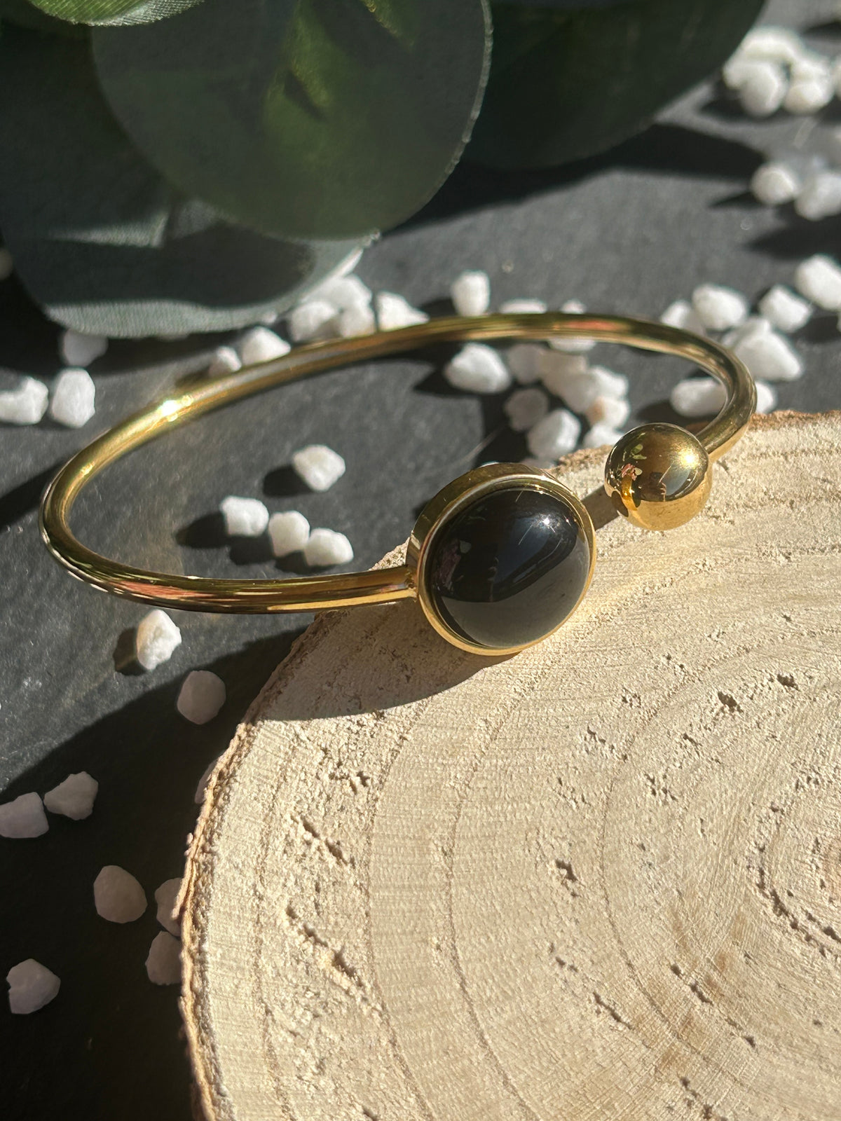 Bracelet jonc Lunae en acier inoxydable doré, orné d’un cabochon rond de 12 mm en agate noire naturelle et d’une bille fixe.