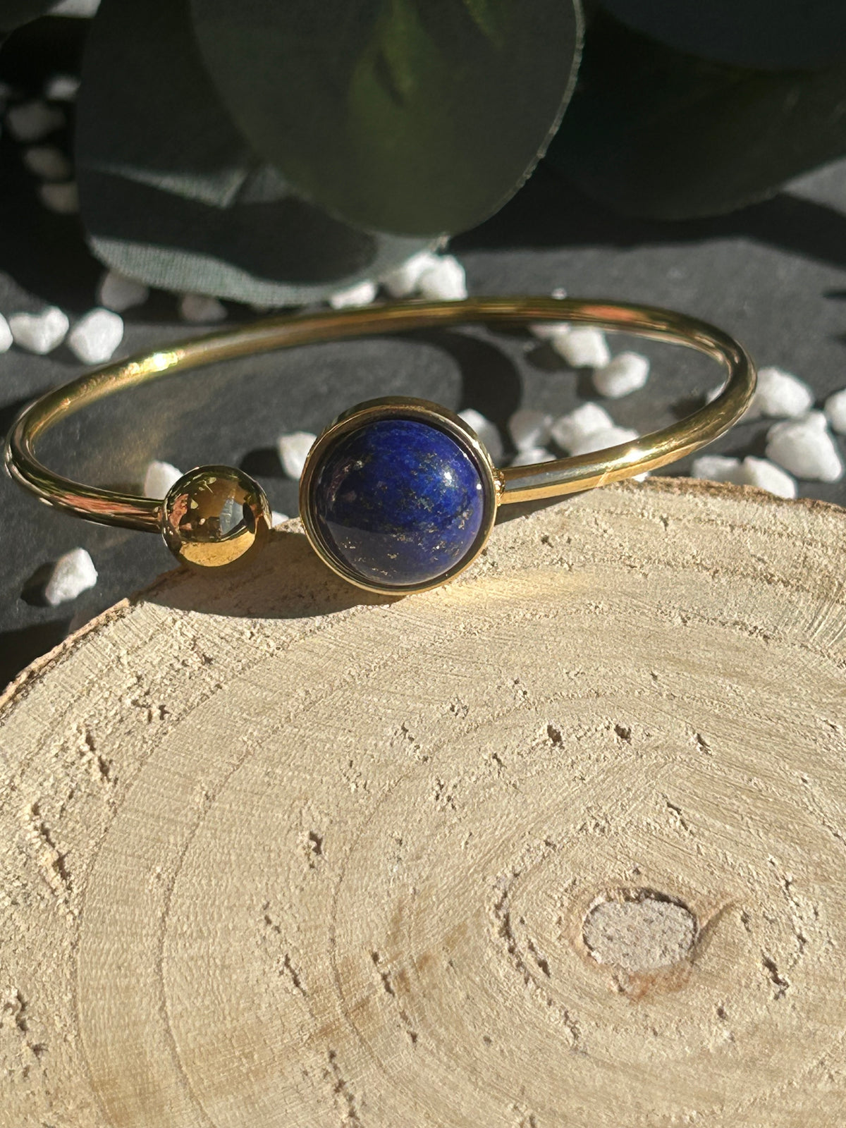 Bracelet jonc Lunae en acier inoxydable doré, orné d’un cabochon rond de 12 mm en lapis-lazuli bleu profond et d’une bille fixe.