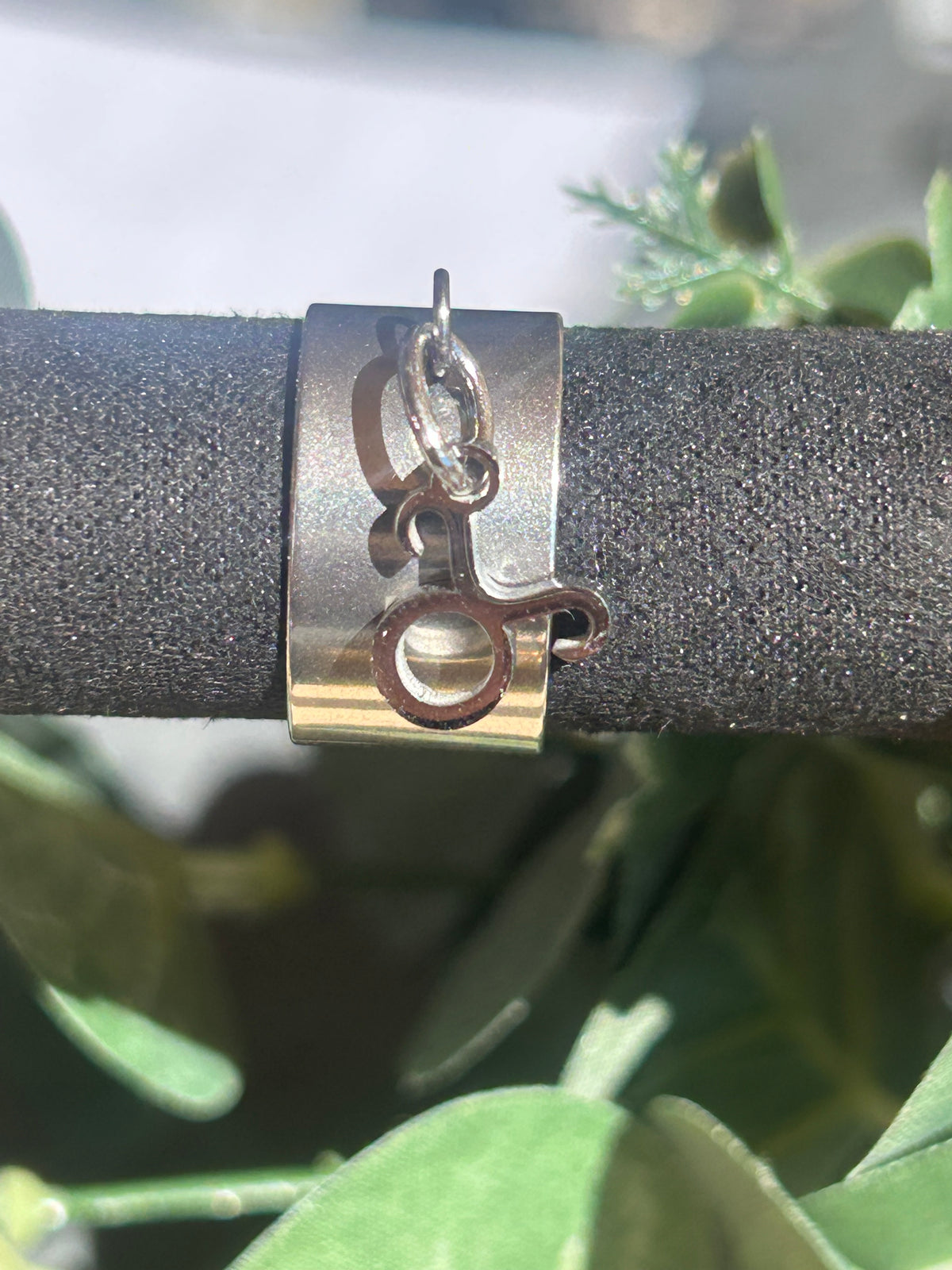 Bague Cassiopée à monture large en acier inoxydable argenté, avec une breloque du signe du Taureau suspendue.