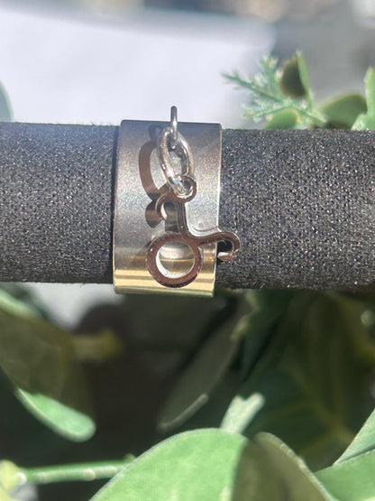 Bague Cassiopée à monture large en acier inoxydable argenté, avec une breloque du signe du Taureau suspendue.