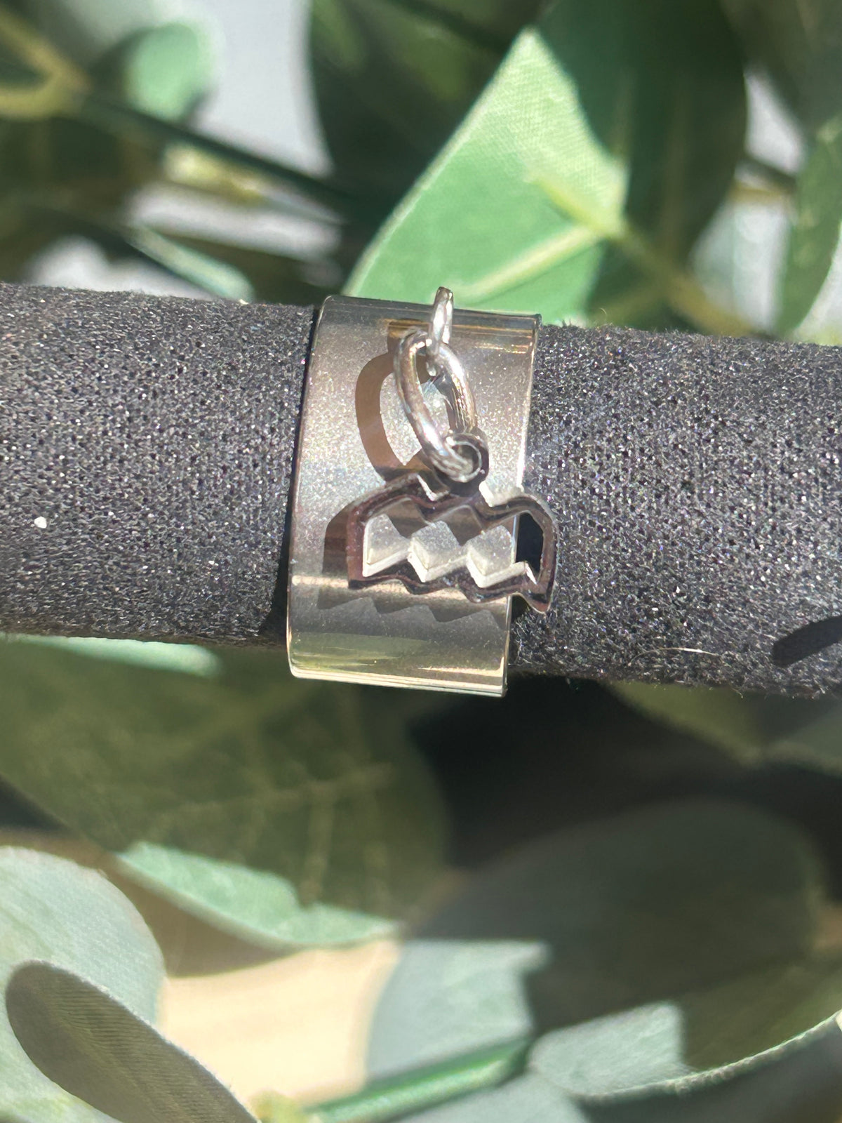 Bague Cassiopée à monture large en acier inoxydable argenté, avec une breloque du signe du Verseau suspendue.