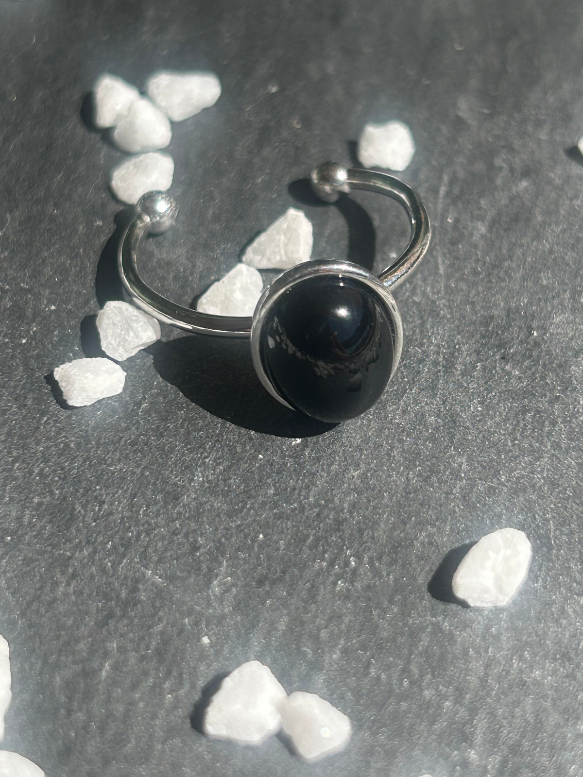Bague Thémis réglable en acier inoxydable argenté, ornée d’un cabochon ovale en agate noire.