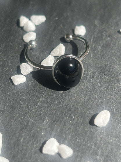Bague Thémis réglable en acier inoxydable argenté, ornée d’un cabochon ovale en agate noire.