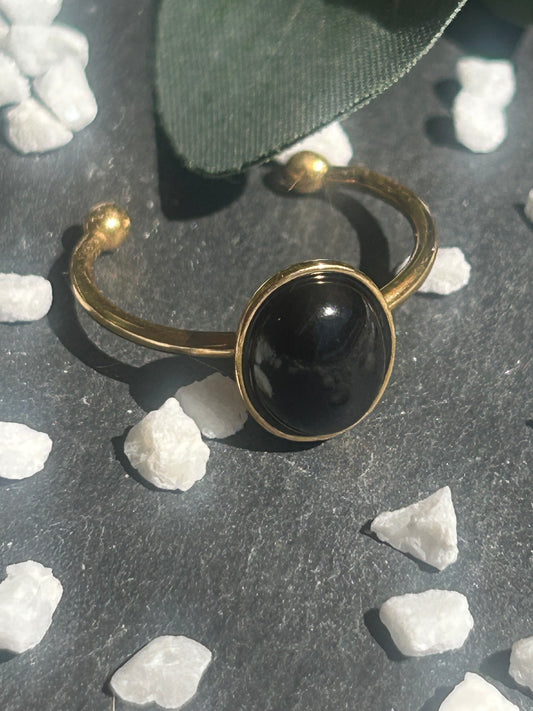 Bague Thémis réglable en acier inoxydable doré, ornée d’un cabochon ovale en agate noire.