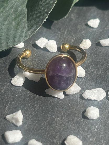 Bague Thémis réglable en acier inoxydable doré, ornée d’un cabochon ovale en améthyste violette.