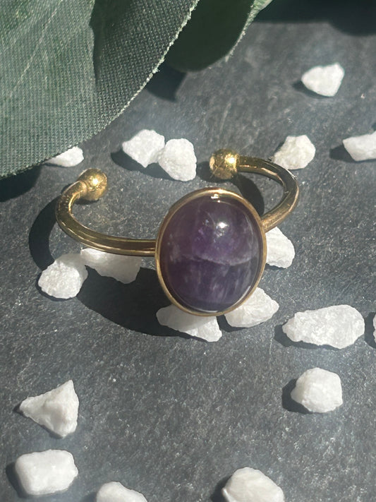Bague Thémis réglable en acier inoxydable doré, ornée d’un cabochon ovale en améthyste violette.