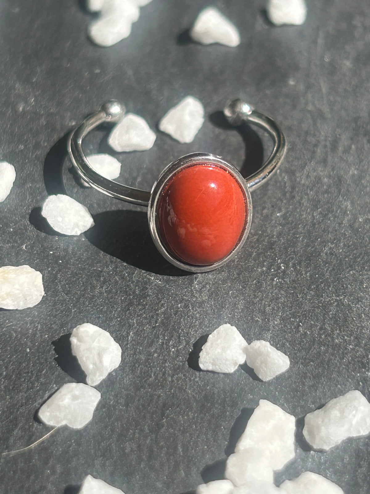 Bague Thémis réglable en acier inoxydable argenté, ornée d’un cabochon ovale en jaspe rouge.