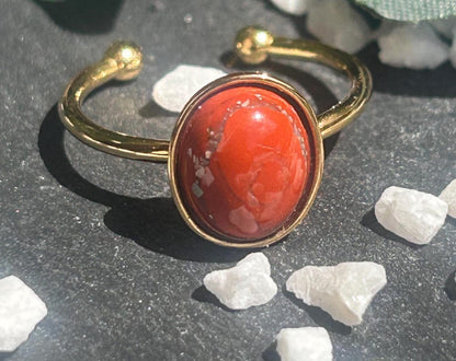 Bague Thémis réglable en acier inoxydable doré, ornée d’un cabochon ovale en jaspe rouge.