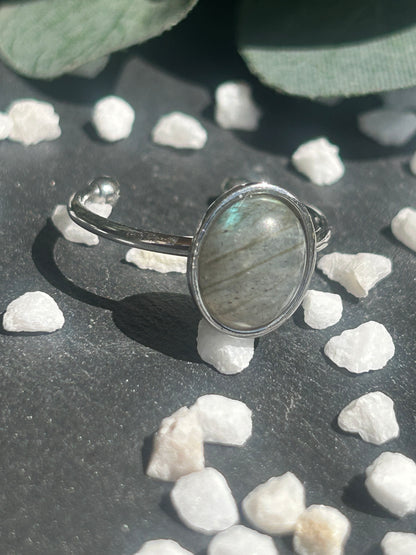 Bague Thémis réglable en acier inoxydable argenté, ornée d’un cabochon ovale en labradorite aux nuances grises.