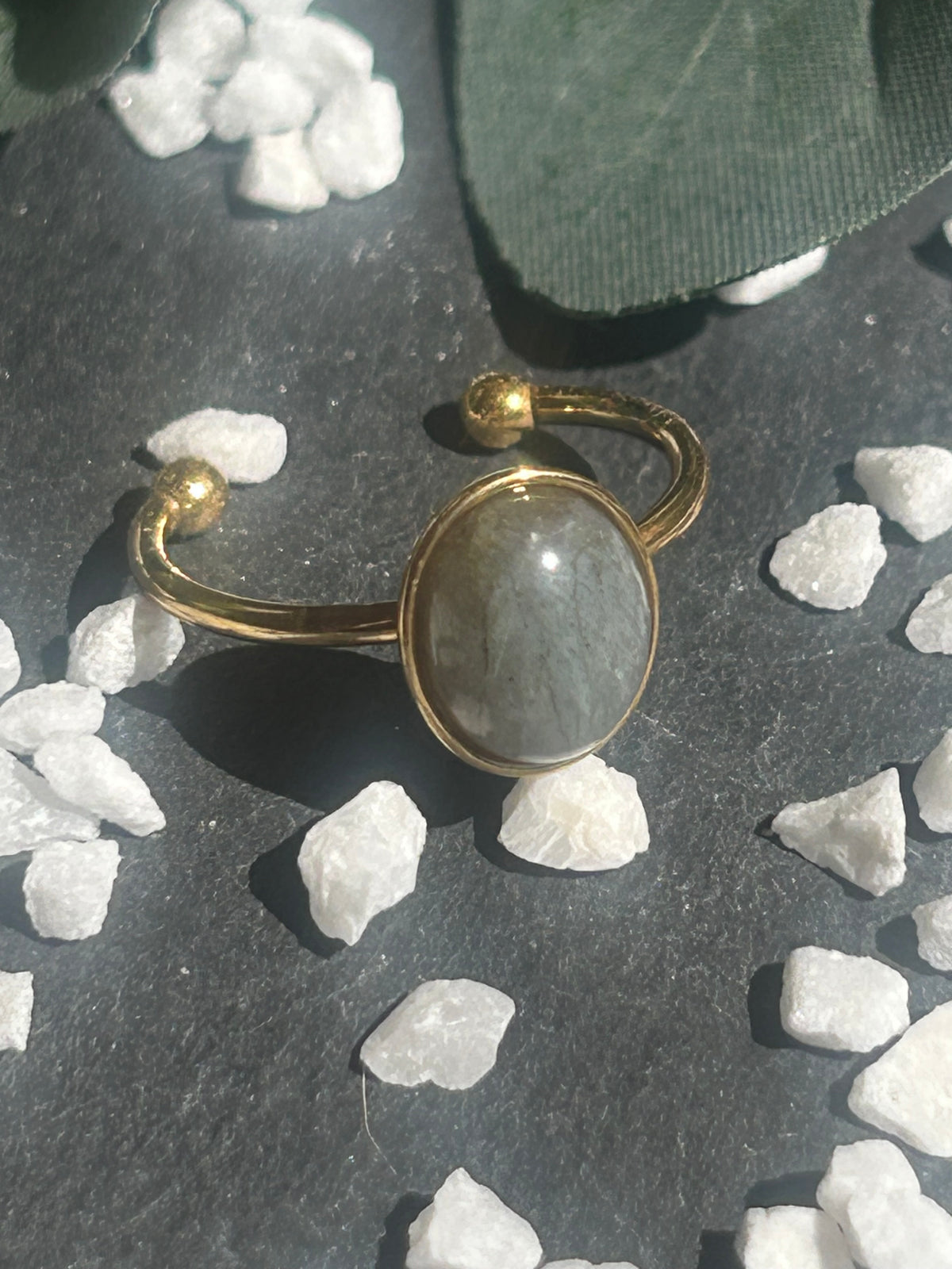 Bague Thémis réglable en acier inoxydable doré, ornée d’un cabochon ovale en labradorite aux nuances grises.