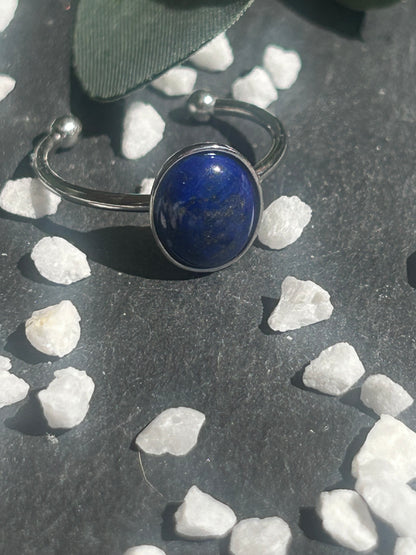 Bague Thémis réglable en acier inoxydable argenté, ornée d’un cabochon ovale en lapis-lazuli bleu profond.