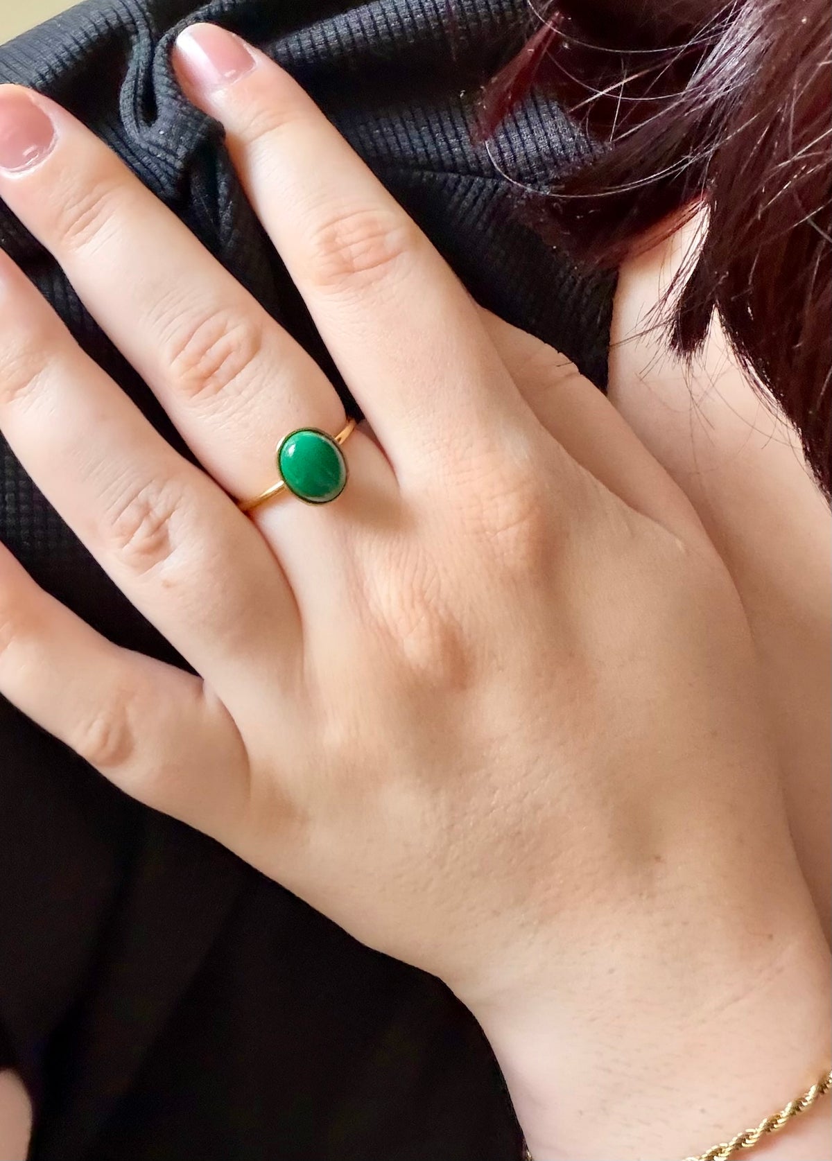 Bague Thémis portée à la main, en acier inoxydable doré avec un cabochon ovale en malachite verte.