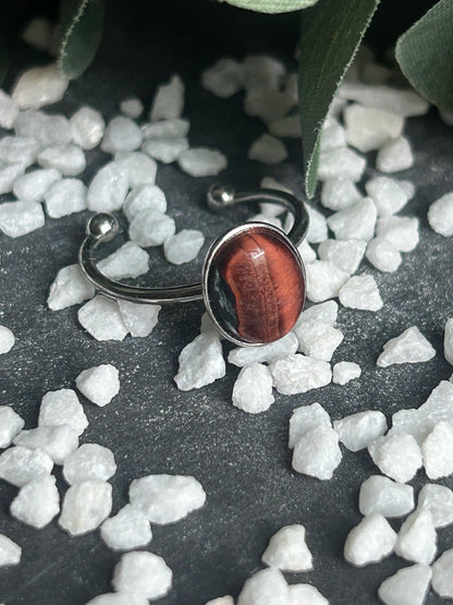 Bague Thémis réglable en acier inoxydable argenté, ornée d’un cabochon ovale en œil de taureau aux nuances rouge brun.