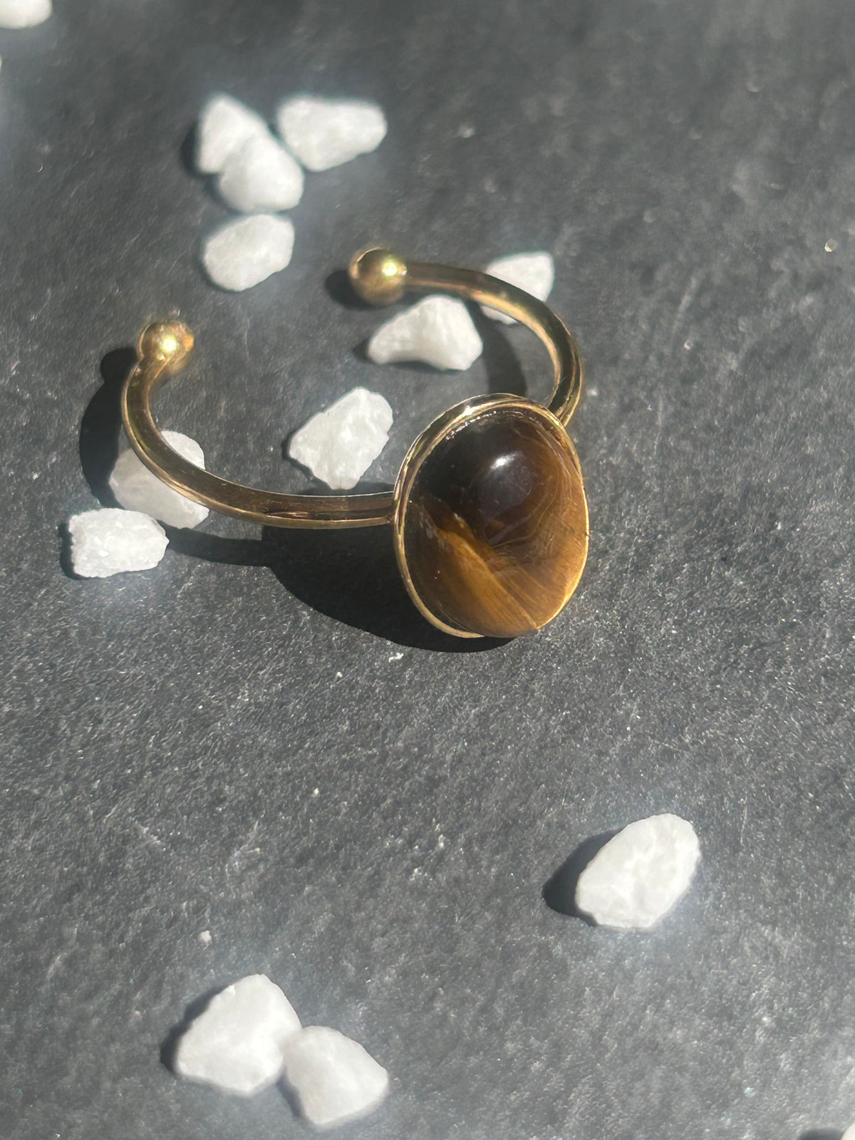 Bague Thémis réglable en acier inoxydable doré, ornée d’un cabochon ovale en œil de tigre brun doré.