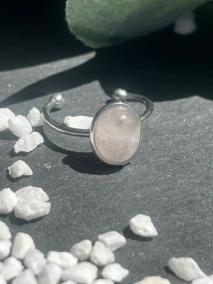 Bague Thémis réglable en acier inoxydable argenté, ornée d’un cabochon ovale en quartz rose pâle.