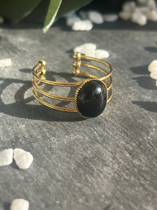 Bague Trinæa réglable à trois anneaux en acier inoxydable doré, ornée d’une agate noire ovale.