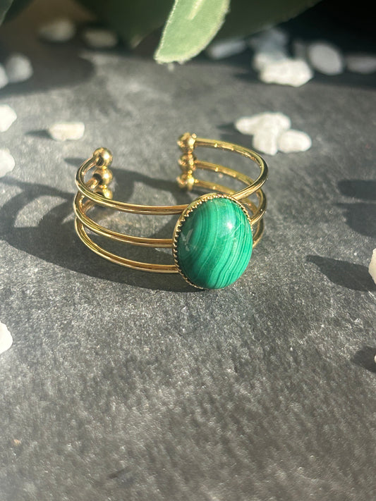 Bague Trinæa réglable à trois anneaux en acier inoxydable doré, ornée d’une malachite ovale aux motifs verts.