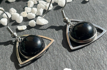 Paire de boucles d’oreilles pendantes Aeltria en acier inoxydable argenté, avec des montures triangulaires et des cabochons ronds en agate noire.