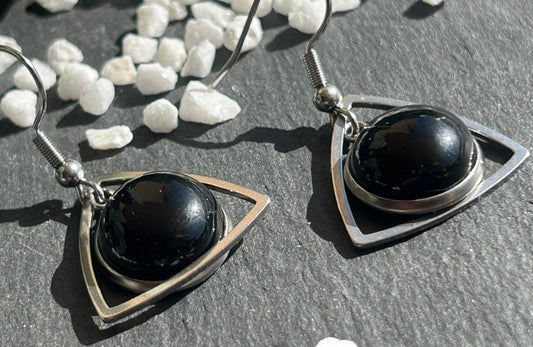 Paire de boucles d’oreilles pendantes Aeltria en acier inoxydable argenté, avec des montures triangulaires et des cabochons ronds en agate noire.