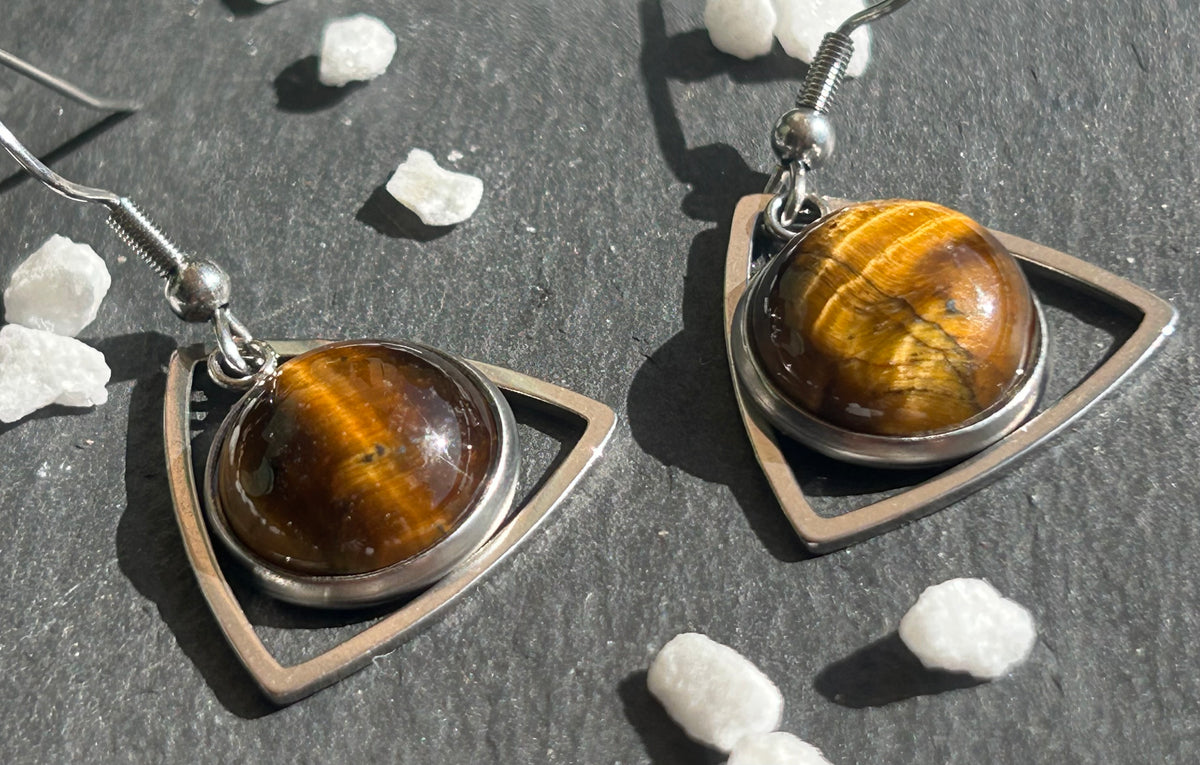 Paire de boucles d’oreilles pendantes Aeltria en acier inoxydable argenté, avec des montures triangulaires et des cabochons ronds en œil de tigre brun doré.
