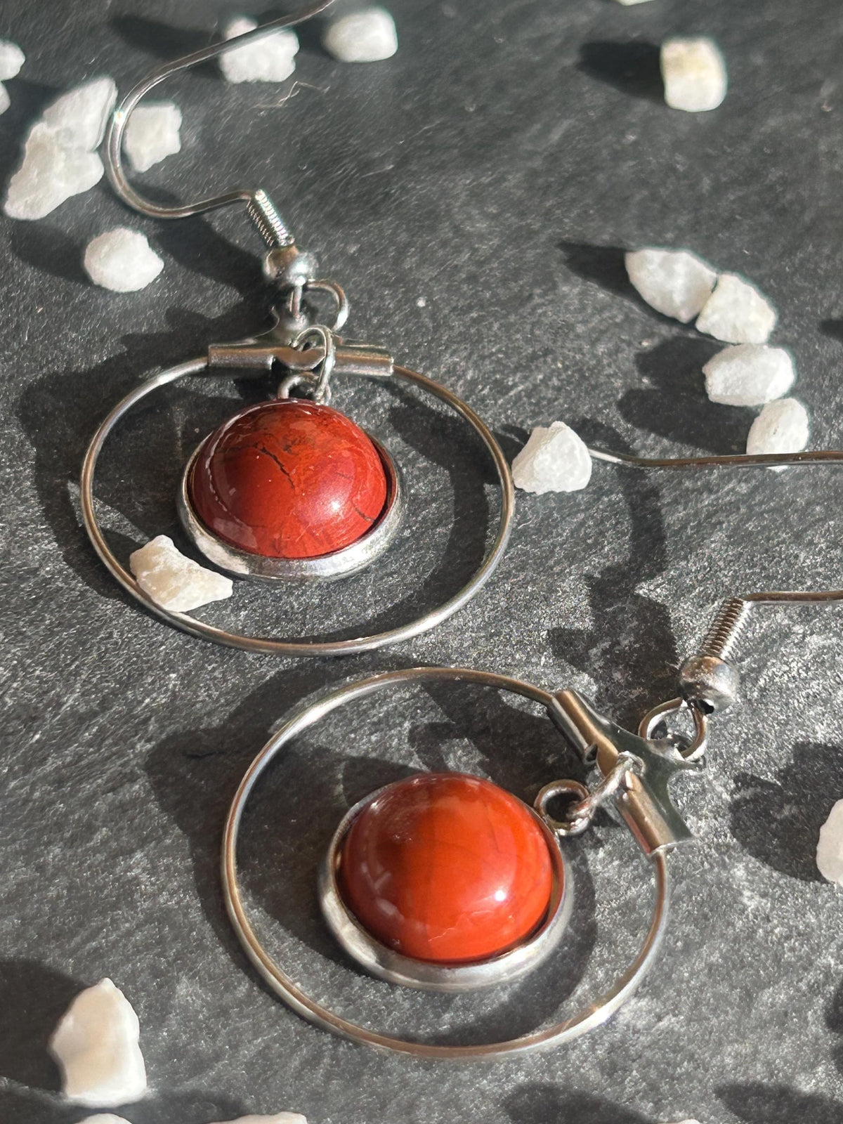 Paire de boucles d’oreilles pendantes Célestia en acier inoxydable argenté, avec des montures circulaires et des cabochons ronds en jaspe rouge.
