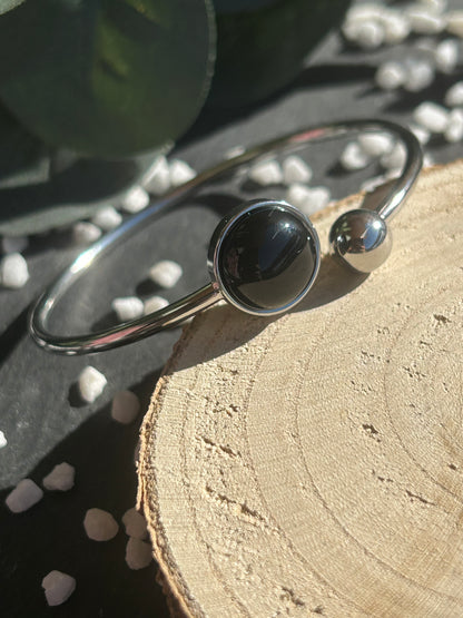 Bracelet jonc Lunae en acier inoxydable argenté, orné d’un cabochon rond de 12 mm en agate noire naturelle et d’une bille fixe.