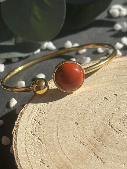 Bracelet jonc Lunae en acier inoxydable doré, orné d’un cabochon rond de 12 mm en jaspe rouge naturel et d’une bille fixe.
