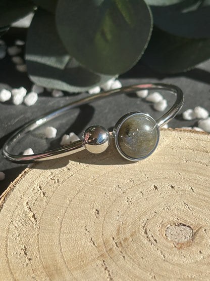 Bracelet jonc Lunae en acier inoxydable argenté, orné d’un cabochon rond de 12 mm en labradorite naturelle et d’une bille fixe.