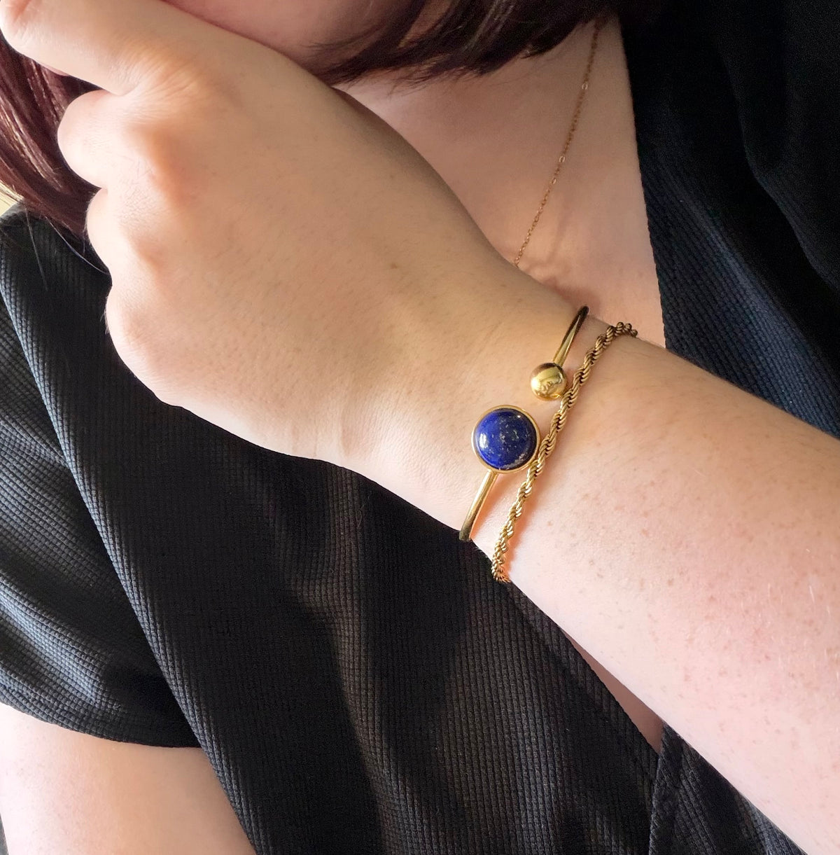 Bracelet jonc Lunae porté au poignet, en acier inoxydable doré avec un cabochon rond en lapis-lazuli bleu profond.