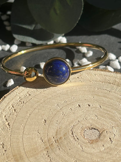 Bracelet jonc Lunae en acier inoxydable doré, orné d’un cabochon rond de 12 mm en lapis-lazuli bleu profond et d’une bille fixe.