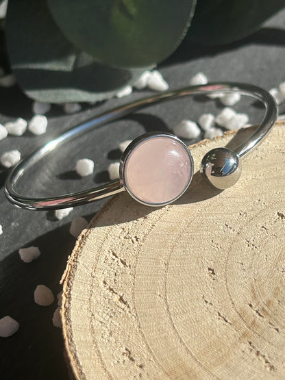 Bracelet jonc Lunae en acier inoxydable argenté, orné d’un cabochon rond de 12 mm en quartz rose naturel et d’une bille fixe.