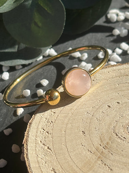 Bracelet jonc Lunae en acier inoxydable doré, orné d’un cabochon rond de 12 mm en quartz rose naturel et d’une bille fixe.