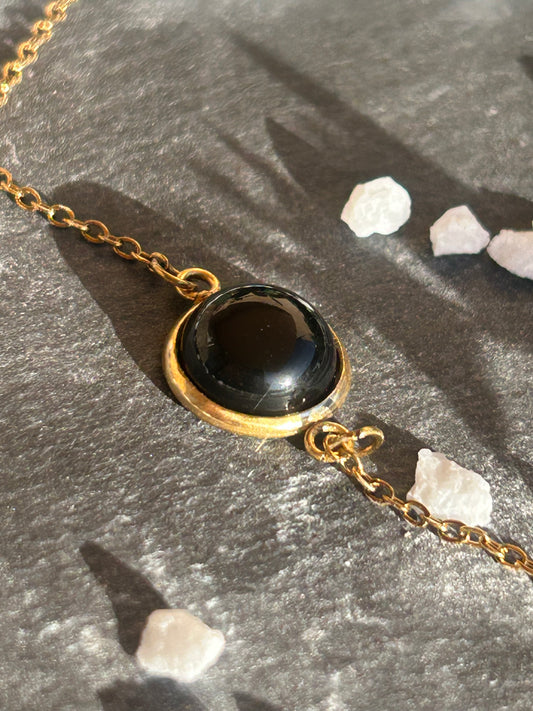 Bracelet Séléna en acier inoxydable doré, orné d’un cabochon rond de 10 mm en agate noire naturelle.