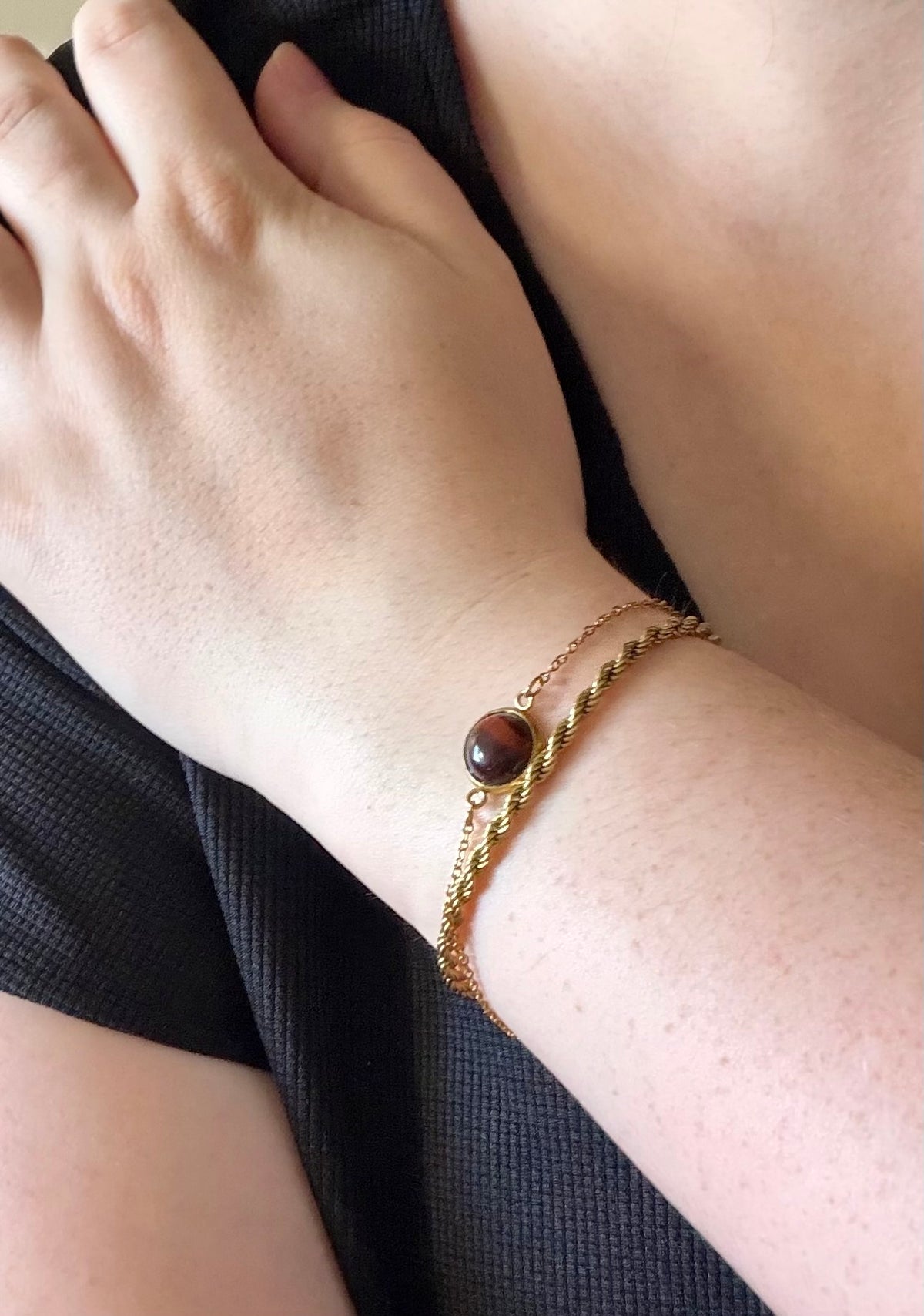 Gros plan du bracelet Séléna porté au poignet, en acier inoxydable doré avec un cabochon rond en œil de taureau.