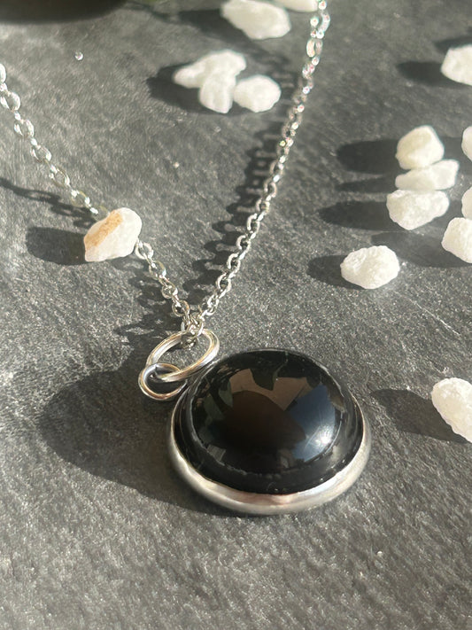Collier Séléna en acier inoxydable argenté, avec pendentif rond de 14 mm en agate noire naturelle.